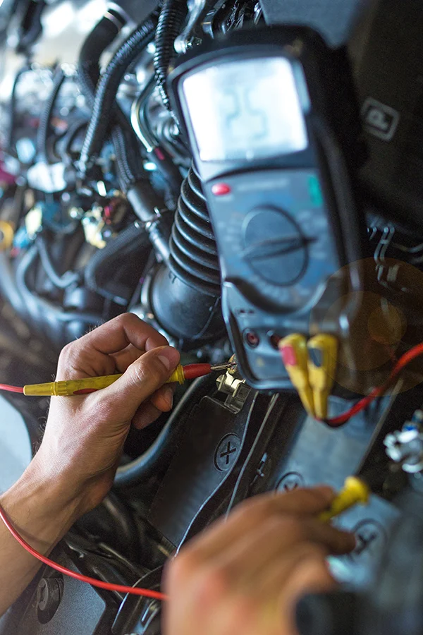 Technician testing vehicle wiring with a digital multimeter